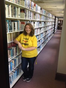 Katelyn smiles while leaning on the stacks